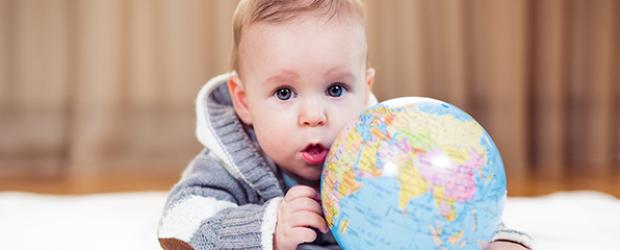 Baby liegt hinter einem Globus