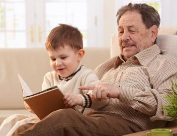 Ein Großvater ließt seinem kleinen Enkel aus einem Buch vor