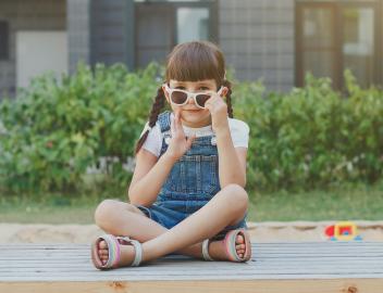 Ein 4-jähriges Mädchen sitzt im türkischen Stil auf einem Spielplatz.